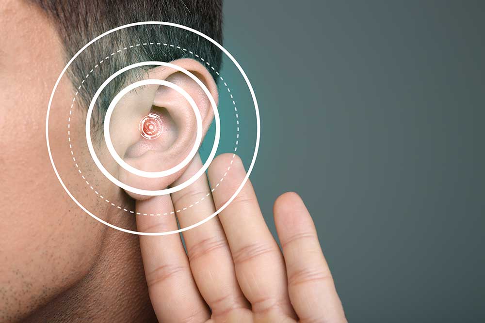 A person holding their hand up to their ear, with concentric circles digitally overlaid to illustrate hearing or sound waves. The background is plain and out of focus.